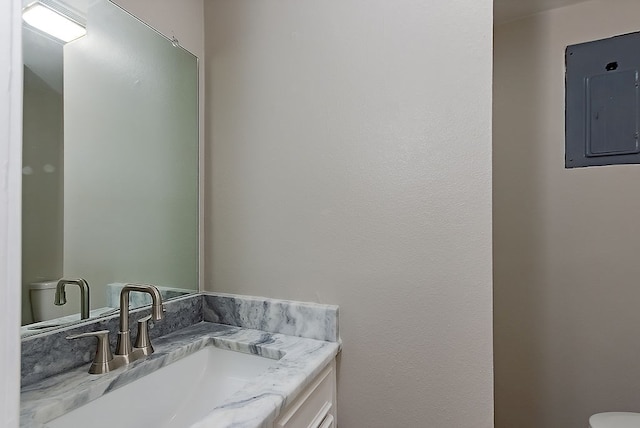 half bath featuring vanity, toilet, and electric panel