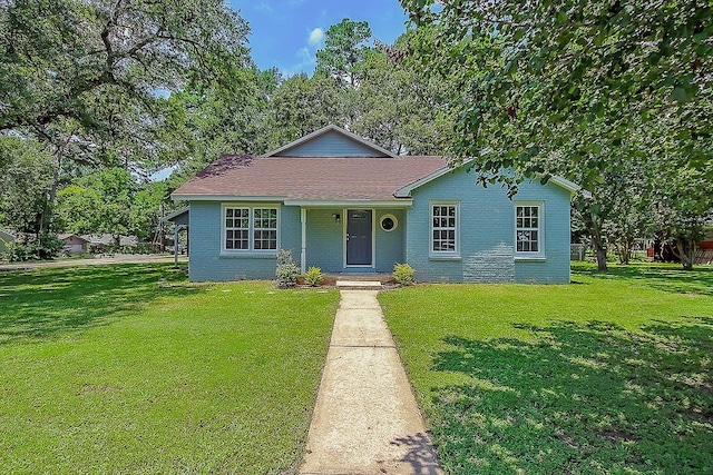 view of front facade featuring brick siding, a front yard, and roof with shingles