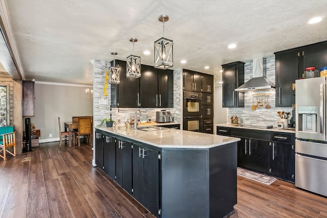 kitchen with black appliances, sink, hanging light fixtures, wall chimney exhaust hood, and dark hardwood / wood-style flooring