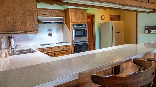 kitchen featuring white appliances, sink, a breakfast bar area, and backsplash