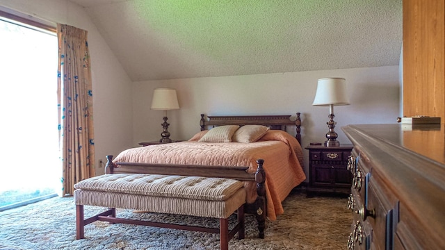 bedroom featuring multiple windows, vaulted ceiling, a textured ceiling, and dark colored carpet