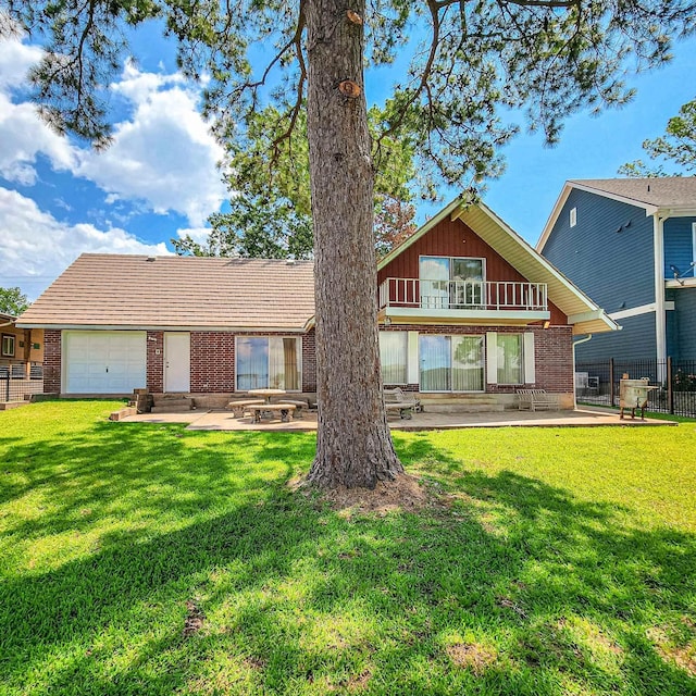 back of property with a balcony, a garage, a patio, and a lawn