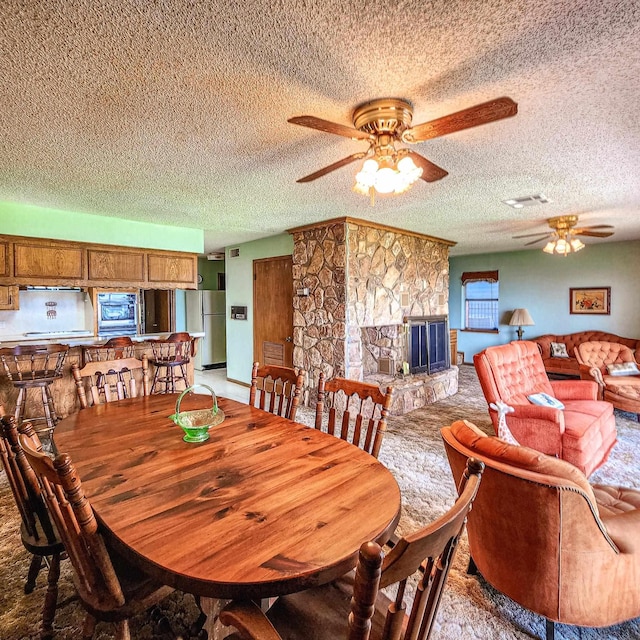 dining space featuring ceiling fan, a fireplace, and a textured ceiling