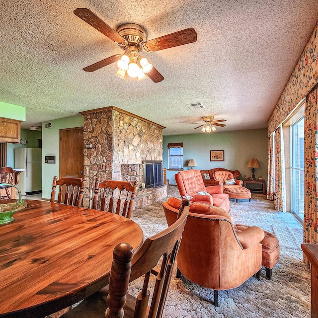 dining area with ceiling fan, carpet, a textured ceiling, and a fireplace