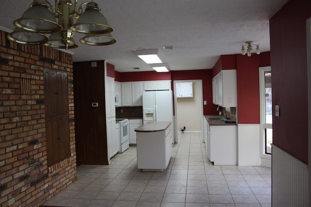 kitchen featuring light tile patterned flooring, white appliances, white cabinets, a textured ceiling, and a kitchen island