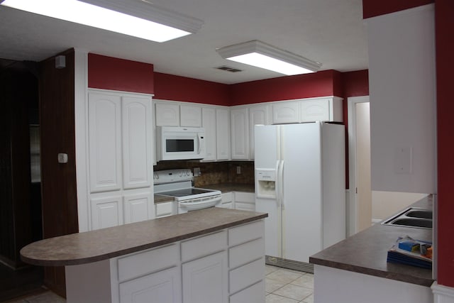 kitchen featuring backsplash, white appliances, white cabinets, a center island, and light tile patterned flooring