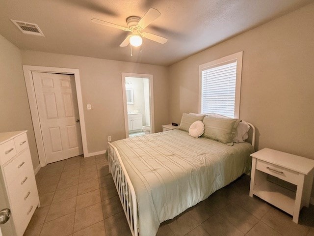 bedroom with ceiling fan, dark tile patterned flooring, ensuite bath, and a textured ceiling