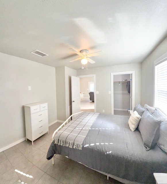 bedroom with a spacious closet, ceiling fan, and a closet