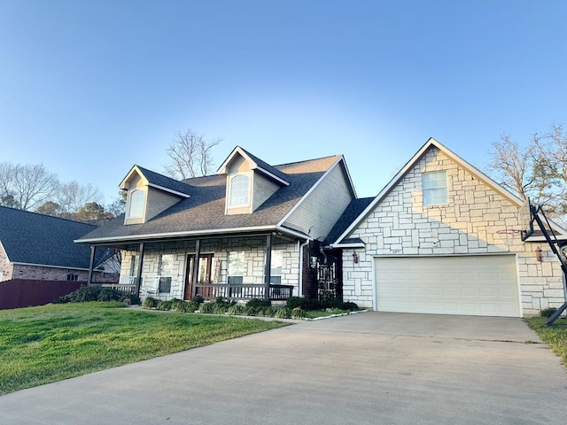 cape cod home featuring driveway, stone siding, an attached garage, a porch, and a front yard