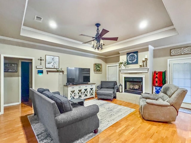 living area with a raised ceiling, visible vents, and wood finished floors