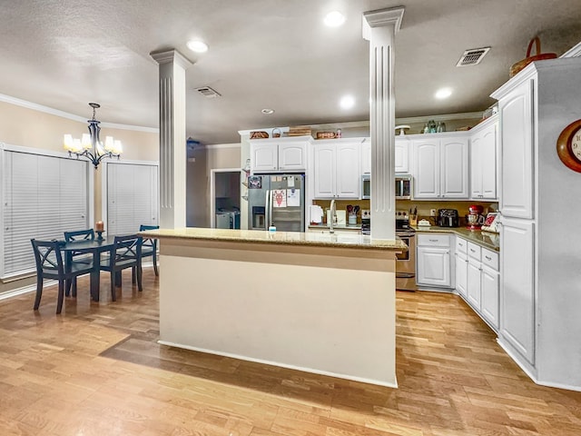 kitchen with decorative columns, white cabinetry, a chandelier, and appliances with stainless steel finishes