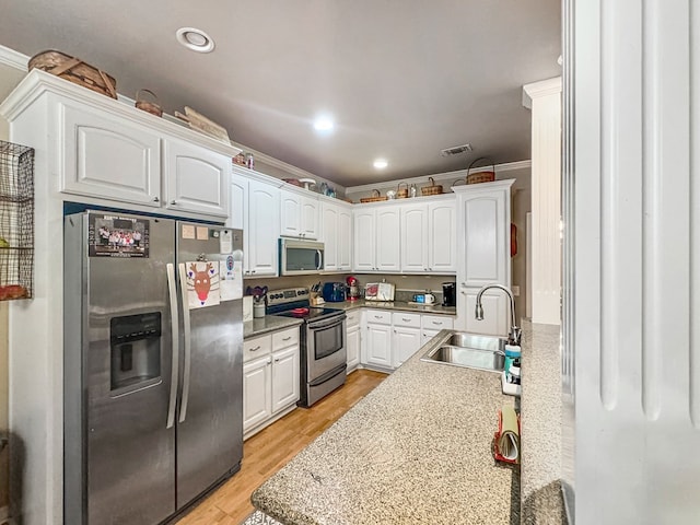 kitchen featuring sink, white cabinetry, light wood-type flooring, crown molding, and appliances with stainless steel finishes