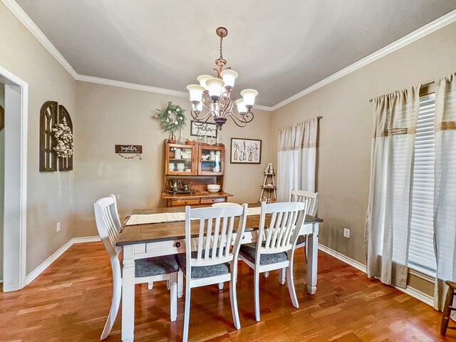 dining area with crown molding, light wood-type flooring, and a notable chandelier