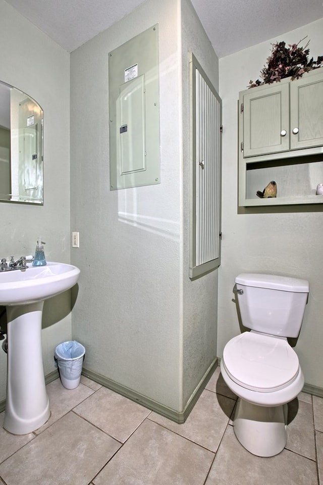 bathroom with electric panel, tile patterned flooring, a textured ceiling, and toilet