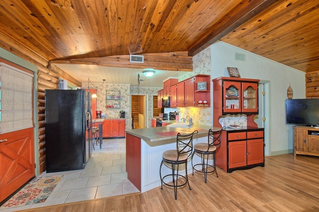 kitchen featuring sink, light hardwood / wood-style flooring, kitchen peninsula, a breakfast bar, and black appliances