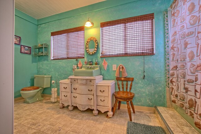 bathroom with walk in shower, sink, and toilet