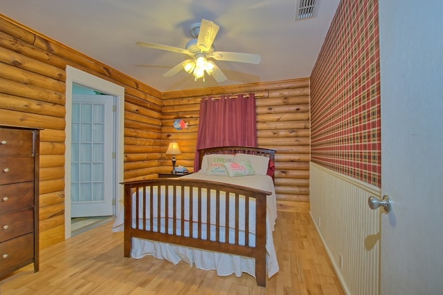 bedroom with ceiling fan, log walls, and light hardwood / wood-style flooring