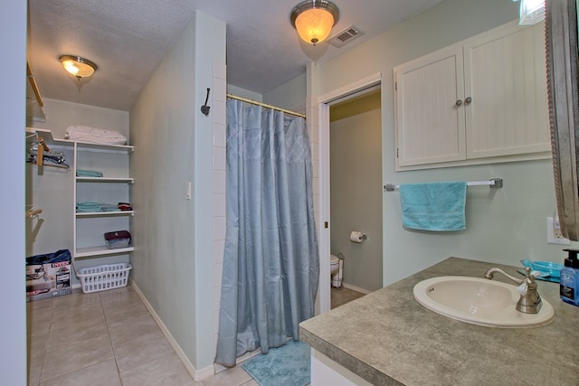 bathroom with vanity, tile patterned floors, toilet, a textured ceiling, and walk in shower