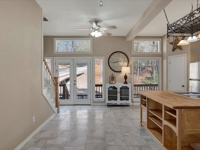 doorway to outside featuring ceiling fan, beam ceiling, a high ceiling, and french doors