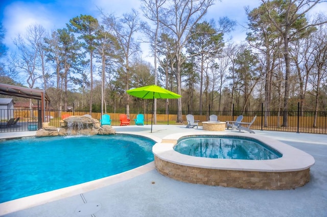 view of pool featuring a patio area, a pool with connected hot tub, an outdoor fire pit, and fence