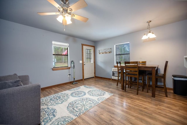 foyer with heating unit, baseboards, wood finished floors, and ceiling fan with notable chandelier