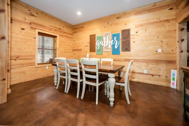 dining area with wood walls and concrete floors