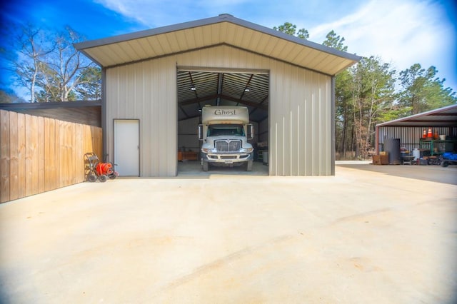 detached garage featuring driveway and fence