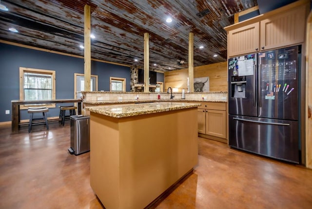 kitchen with finished concrete flooring, wood ceiling, light stone counters, refrigerator with ice dispenser, and a peninsula