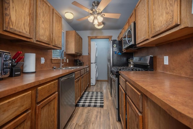 kitchen with light wood finished floors, butcher block countertops, brown cabinets, appliances with stainless steel finishes, and a sink