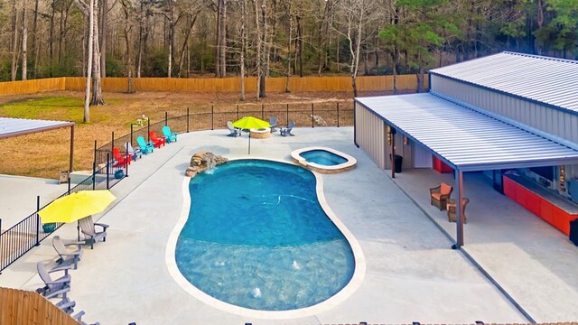 view of pool with a patio area, a pool with connected hot tub, and fence