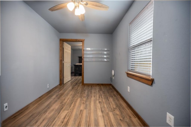 spare room with baseboards, a ceiling fan, and wood finished floors