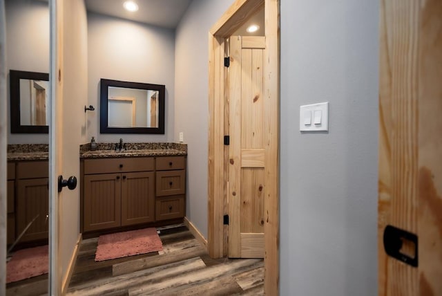 bathroom with vanity, recessed lighting, wood finished floors, and baseboards