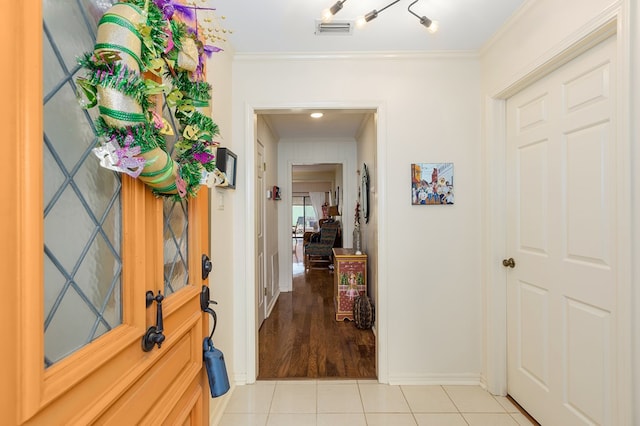 foyer entrance with ornamental molding and light tile patterned floors