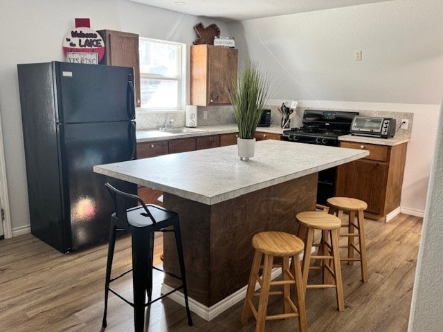 kitchen with a kitchen island, a breakfast bar area, light wood-type flooring, and black appliances