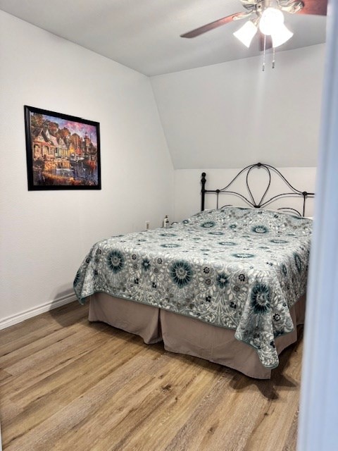 bedroom with hardwood / wood-style flooring, ceiling fan, and vaulted ceiling