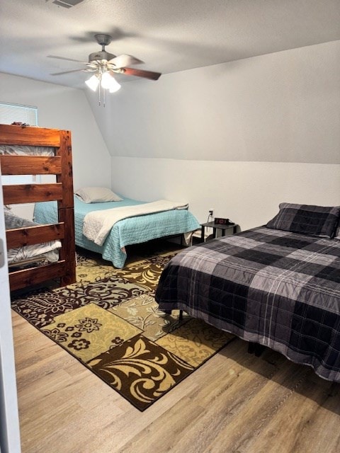 bedroom featuring ceiling fan, lofted ceiling, hardwood / wood-style floors, and a textured ceiling