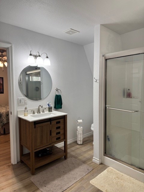 bathroom featuring hardwood / wood-style flooring, vanity, a textured ceiling, a shower with shower door, and toilet