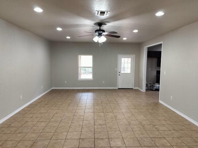 empty room with ceiling fan and light tile patterned floors