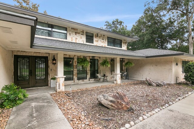 1025 Creek Bend Dr, Jasper, TX 75951 - entrance to property with french doors, roof with shingles, covered porch, and stone siding