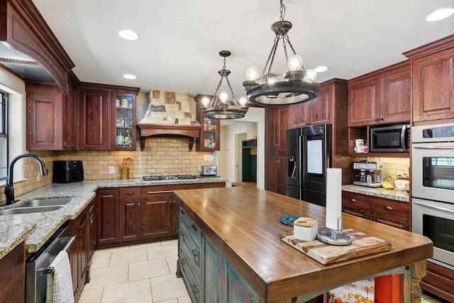 1025 Creek Bend Dr, Jasper, TX 75951 - kitchen with stainless steel appliances, butcher block counters, custom range hood, a chandelier, and decorative backsplash