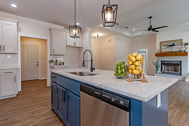 kitchen featuring pendant lighting, dishwasher, sink, blue cabinetry, and white cabinetry