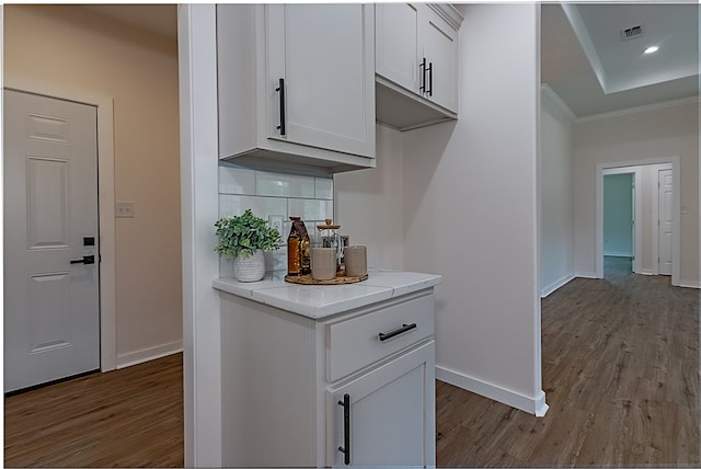 kitchen featuring decorative backsplash, white cabinetry, ornamental molding, and light wood-type flooring