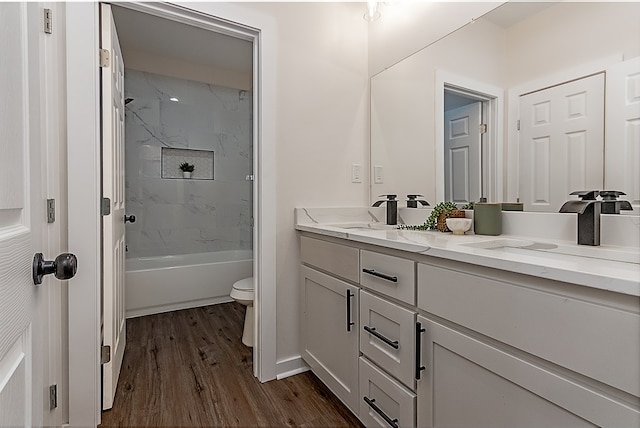 full bathroom with hardwood / wood-style flooring, vanity, toilet, and tiled shower / bath