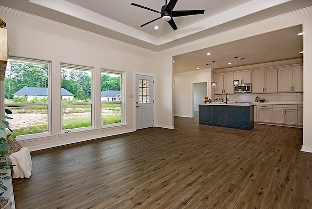 unfurnished living room with dark hardwood / wood-style floors, crown molding, ceiling fan, and a tray ceiling