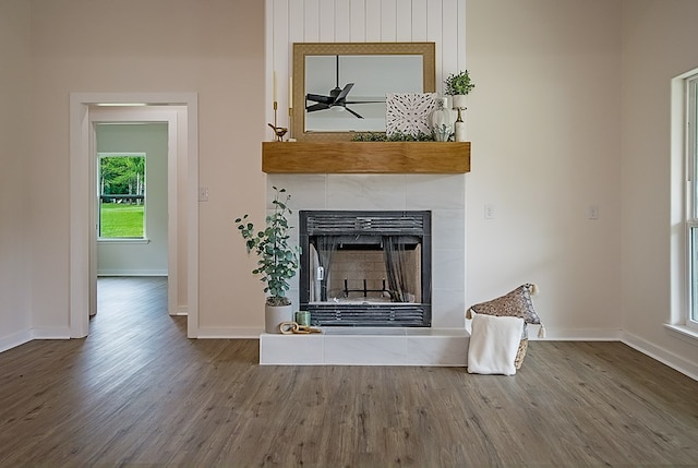 interior details with a tiled fireplace, ceiling fan, and hardwood / wood-style flooring