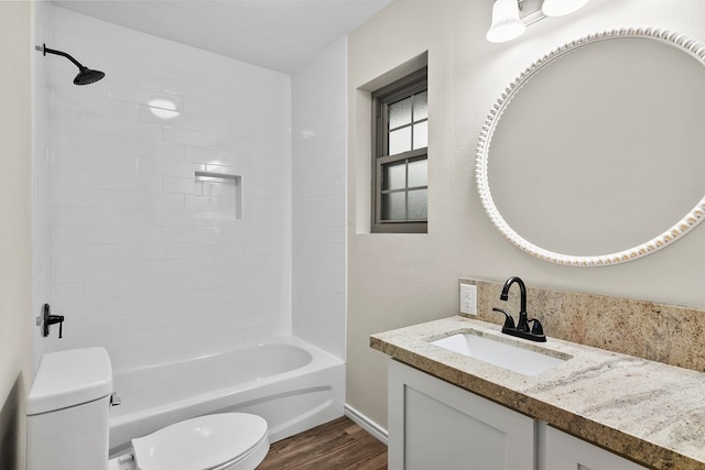 full bathroom featuring hardwood / wood-style floors, tiled shower / bath combo, vanity, a textured ceiling, and toilet