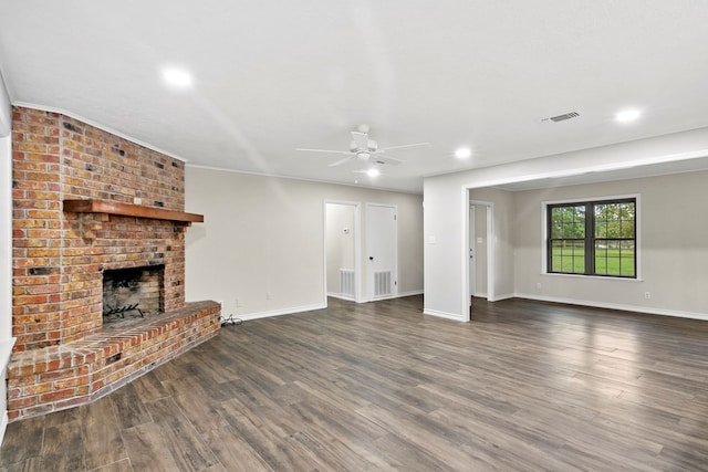 unfurnished living room featuring a brick fireplace, dark wood-type flooring, and ceiling fan