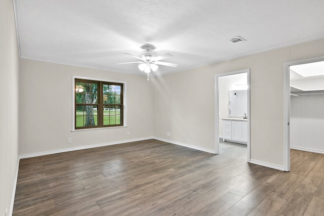 unfurnished bedroom with dark hardwood / wood-style flooring, a spacious closet, crown molding, and a textured ceiling