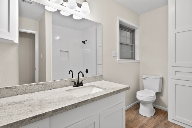 bathroom with vanity, wood-type flooring, a shower, and toilet