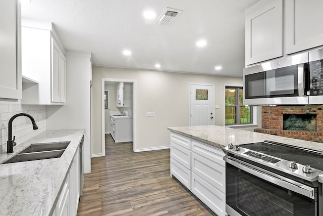 kitchen with hardwood / wood-style floors, white cabinetry, sink, stainless steel appliances, and light stone countertops